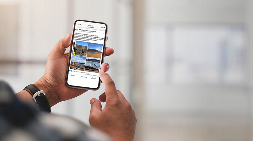 An over-the-shoulder view of a business owner’s mobile phone, displaying images of a building with solar installations, representing how to achieve company ESG goals with solar.