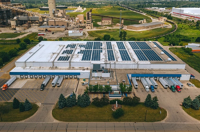 An aerial view of a large building with rooftop solar panels, representing how to achieve company ESG goals with solar.