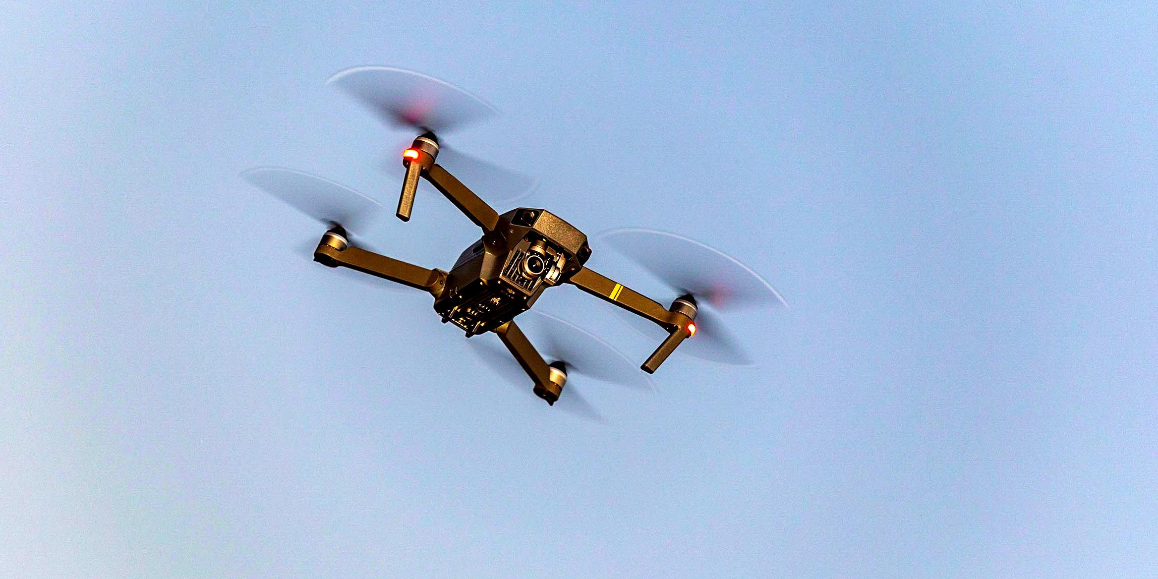 A drone flying across a blue-grey sky, representing drones as solar site survey tools.